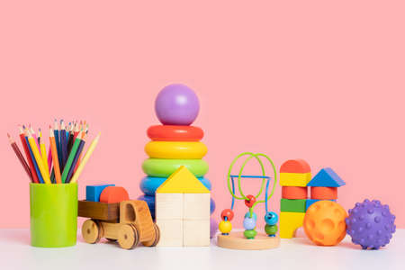 A colorful set of educational toys for preschool children. Wooden and plastic toys on a pink background. copy spaceの写真素材