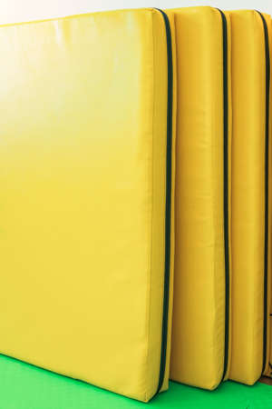 Soft yellow gym mats for jumping stand against the wall in the kindergarten gymの写真素材
