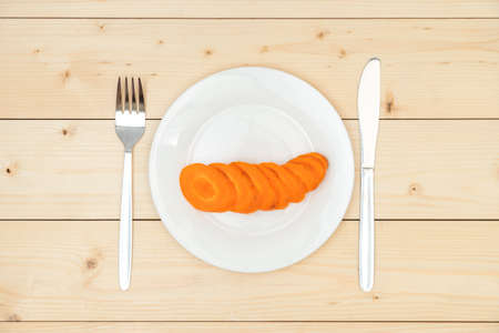 The concept of diet and eating healthy. Raw carrots cut into slices on a white plate, top viewの写真素材