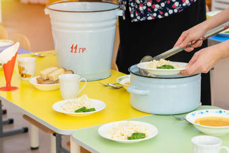 Nannies in the kindergarten are served tables before lunch. close upの写真素材