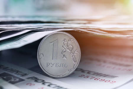 The Russian ruble coin is covered with paper banknotes of one thousand rubles. Sunbeam, soft focusの写真素材