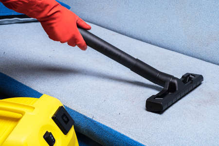 Female hands cleaning the sofa with a washing vacuum cleanerの写真素材