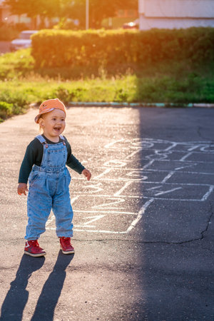 Happy kid laughs while playing hopscotch on the playgroundの写真素材