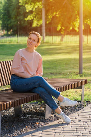 A beautiful brunette aged 30-33 years is resting in the park on a benchの写真素材