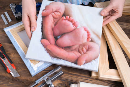 The master demonstrates a photo of children's legs printed on canvas and stretched on a stretcher.の写真素材