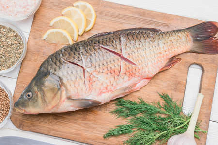 Fresh carp fish with cuts on the soul lies on the cutting board, close-upの写真素材