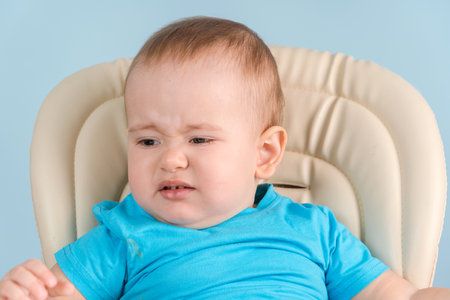 a disgruntled crying toddler of 12-17 months on a feeding chair does not want to have lunch.の写真素材