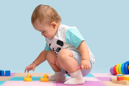 Toddler in the playroom grabs yellow rubber ducks for bathing from the floor.の写真素材