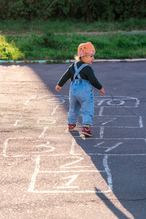 Active 2-year-old girl learns to play hopscotch painted on asphaltの写真素材