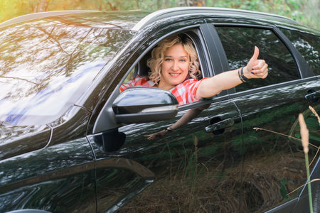 Adult blonde woman gives a thumbs up while sitting inside a carの写真素材