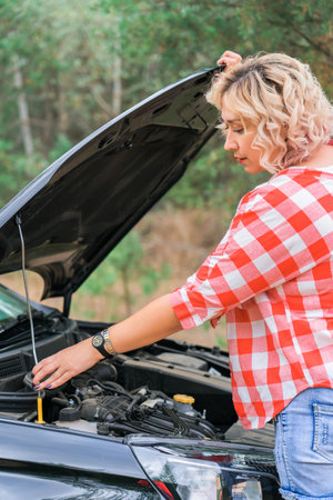 A woman opens the hood of a car, close-upの写真素材