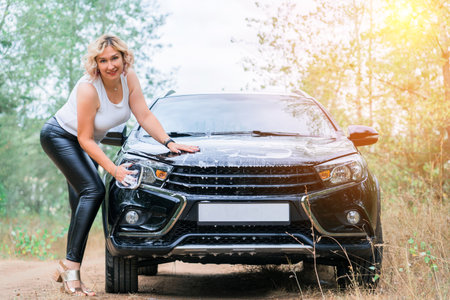 Blonde woman washes car outdoorsの写真素材