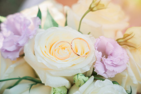 Two wedding rings on a wedding bouquet in the rays of the sun. close-upの写真素材