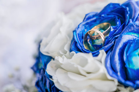 Wedding gold rings on a bouquet of white and blue roses. copyspace.の写真素材