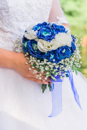 A girl holds a wedding bouquet of white and blue roses, close-up. side view.の写真素材