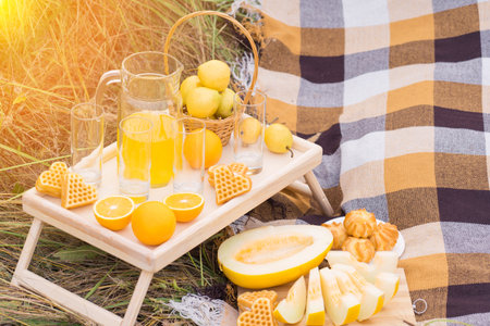 A table with fruits and pastries at a picnic in summer, in the rays of sunset light.の写真素材