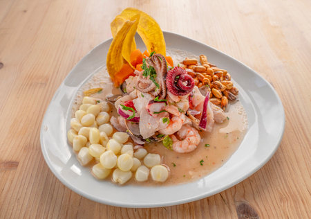 Close-up of Ceviche Mixto, a traditional Peruvian dish with raw fish, lemon juice, onions, aji chili, and corn, garnished with cilantro on a white plate, isolated on a light woodの写真素材