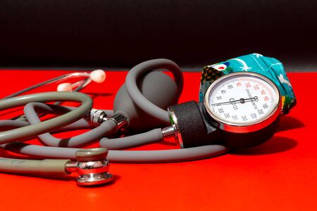 Neonatal stethoscope and Pediatrics sphygmomanometer on red with black background, children and...