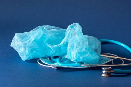 Neonatal blue stethoscope, medical cap and mask on blue dark backgrpund. Medical attention for...
