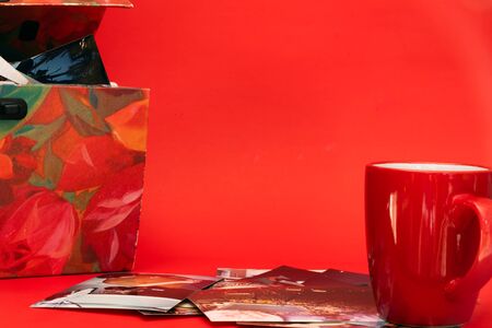 One open old and ware feminine, old pictures box and many pictures scattered plus a red cup all stand on a red background. Memories and nostalgia concept quarantine activities.の写真素材