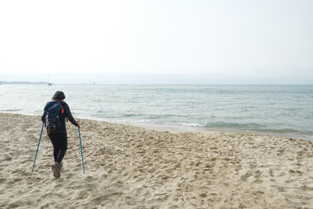February 2021-Nordic walking. Closeup of female legs hiking on the beach. Active and healthy lifestyle. Italyのeditorial素材