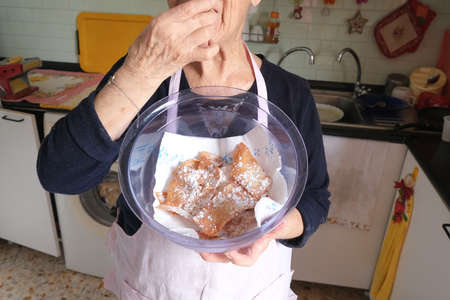 old woman tasting fried cenci, traditional Italian carnival sweet pastryのeditorial素材