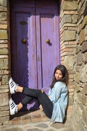 Cute teenage girl sitting the violet door. Italyのeditorial素材