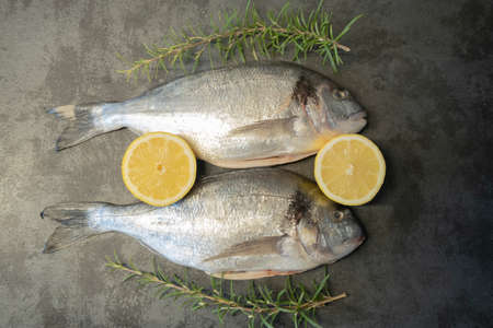 Sea bream or dorado raw fish uncooked with lemon and rosemaryの写真素材