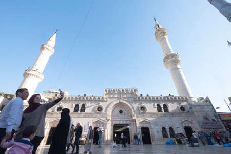 Amman, Jordan: A family taking selfies in front of the Al-Husseini Mosque in the capital of Jordan on a sunny day. Two slender minarets mark the presence of the al-Husseini Mosque.のeditorial素材
