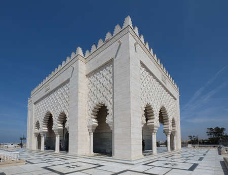 The Mausoleum of Mohammed V against the clear blue sky. The snow-white historical building is located on the opposite side of the Hassan Tower on the Yacoub al-Mansour esplanade in Rabat, Morocco.のeditorial素材