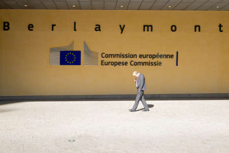 Brussels: Old man walking in front of the Berlaymont building, headquarters of the European commission. An office building in Brussels, Belgium.のeditorial素材