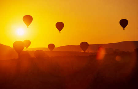 Cappadocia, Turkey: Hot air balloons in the sunset sky. Golden hour. Air balloons before launch in Goreme national park. Balloon laughs in Turkey.の写真素材