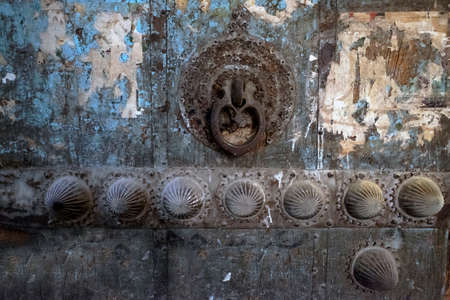 Closeup of the old rustic door. Antique door with a rustic lock. Chipped paint. Metal handle. House entrance. Vintage. Ancient history. Middle east architecture.の写真素材