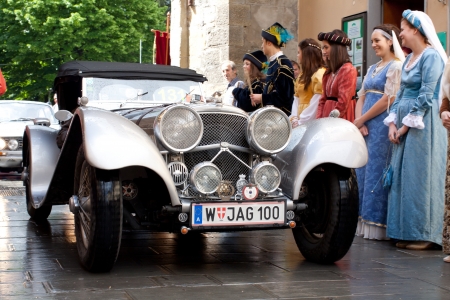 Mille Miglia 2013, Sansepolcro. An old racing car Jaguar 100 (1937) enters the old town of Sansepolcro, between historical dressed people, during the car racing Mille Miglia 2013, re-enactment of the old italian endurance race (1927-1957)のeditorial素材