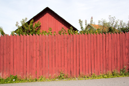Detail of typical Swedish wood house, with fence in the typical red 'falun' colorの写真素材