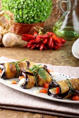 Eggplant rolls with cheese, tomato and basil on complex backgroundの写真素材