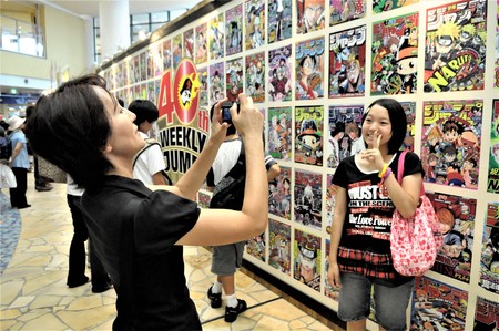 JAPAN, TOKYO, AUGUST 10,2018 A MOTHER TAKES A PICTURE OF HER DAUGHTER IN FRONT OT A WALL FULL OF...