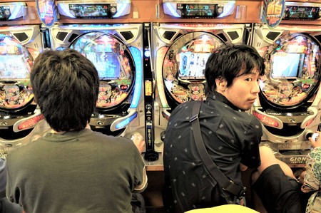 TWO PEOPLE SITTING PLAYING PACHINKO A VERY POPULAR GAMBLING GAMEのeditorial素材