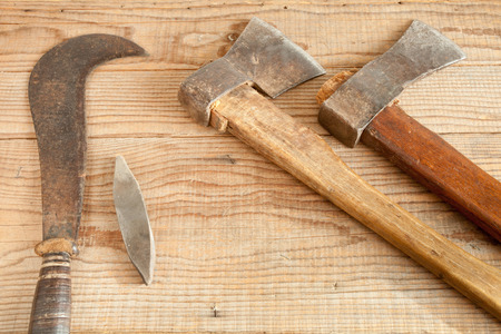Two dated and used cleavers and billhook on wooden background
