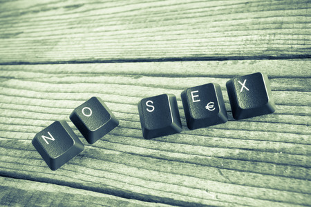 "NO SEX" wrote with keyboard keys on wooden background, green vintage effectの写真素材