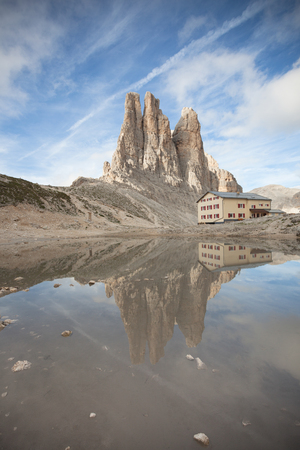 A refuge is reflecting over a little lake next to the Vajolet towersの写真素材