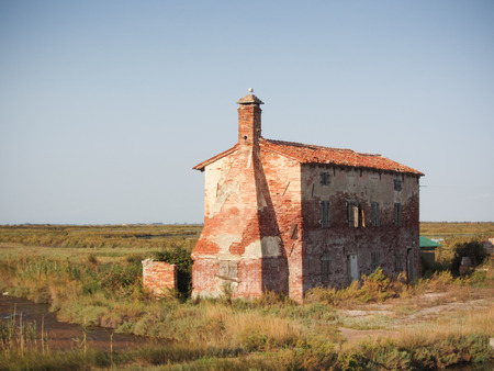 VENICE, ITALY - AUGUST 21, 2017: Old uninhabited house in the late afternoon long the saltmarsh in Lio Piccolo, little town near Veniceのeditorial素材