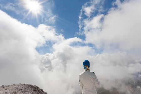 VAL DI FUNES, ITALY - SEPTEMBER 24, 2016: A blonde girl in a sunny day admiring the panorama from a mountain peak in Dolomitesのeditorial素材