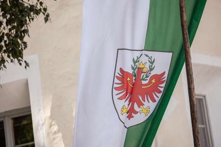 CHIUSA, ITALY - SEPTEMBER 16, 2017: The green and white Alto Adige regional flag is on the wind during the local celebration "Torggelen"  with traditional local clothes, habits and food.のeditorial素材