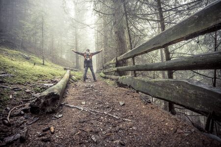a man walking alone inside a forest in a foggy dayの写真素材