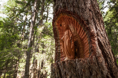 A traditional wooden sculpture for Mary inside a woods on a single tree