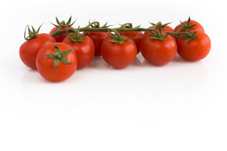 Bunch of cherry tomatoes with green leaves isolated on white background. Still-life studio shot taken with soft-box.の写真素材