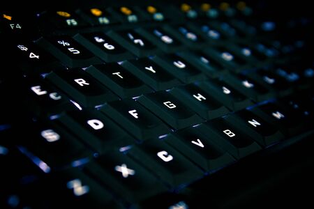 Black computer keyboard with backlit keystrokes.の写真素材