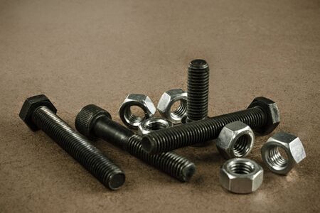 Black bolts and silver nuts scattered on a wooden working table. Picture taken in with soft-box studio.の写真素材