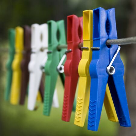 Multi colored clothespins hanging on a wire outdoors